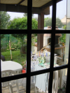 Vue depuis la grande fenetre du salon sur la terrasse, le jardin et le bbq