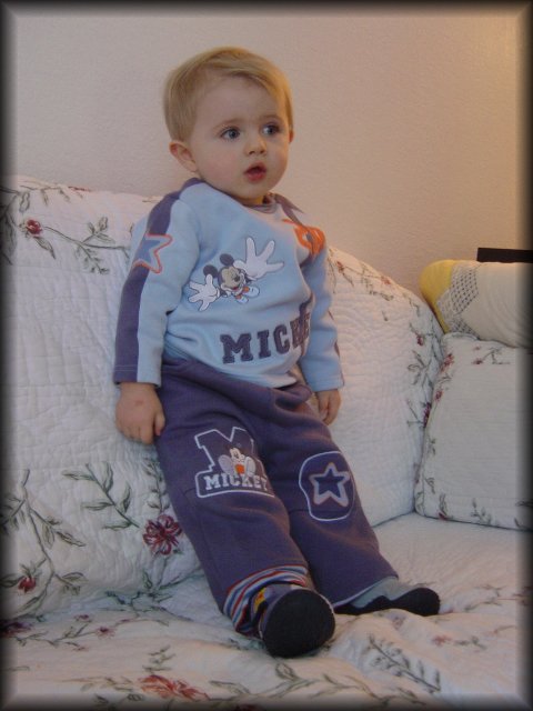 Alexis still standing up on the couch, leaning, mesmerised by the TV