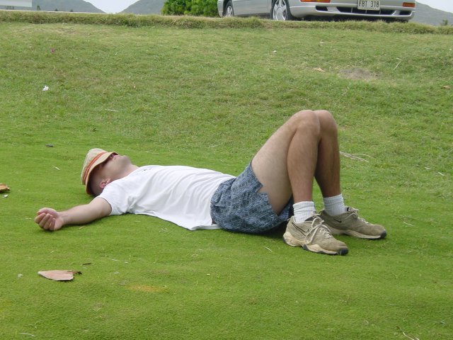 Dean sprawled in the grass, a hat over his face