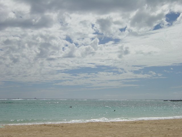 Beach, silver ocean below a blue and white sky