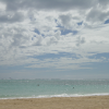 Beach, silver ocean below a blue and white sky