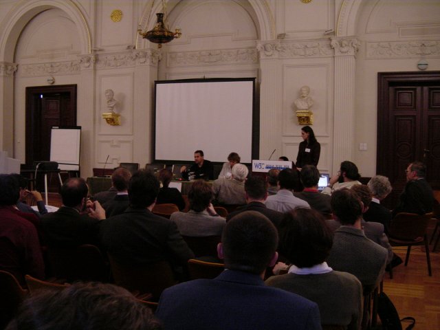 View from the back of the room of the attendees, Daniel, Marie and Eva at the front