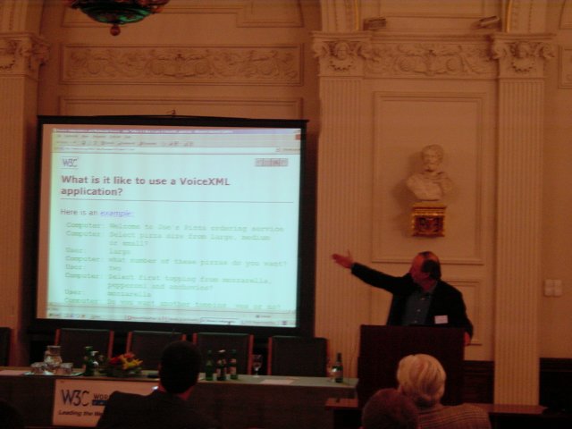 Vincent pointing an arm to the slide "what is it like to use a VoiceXML application?"