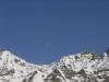 La lune juste au dessus de la montagne enneigee et dans un ciel bien bleu