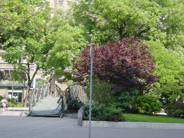 Statue of a bridge and a man standing on it looking into water