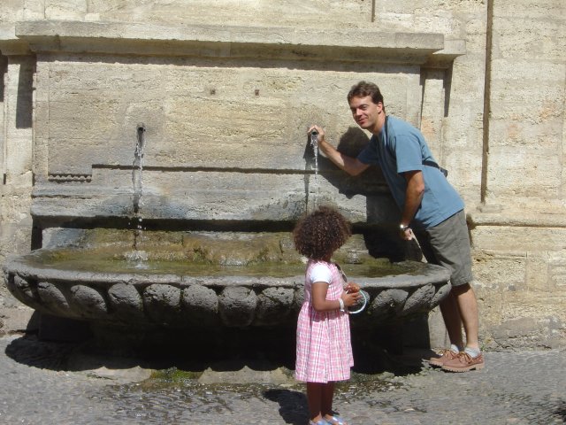 Steph se desaltere a une fontaine sous le regard intrigue' d'une petite fille