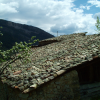A roof with colourful and uneven tiles under a deep blue sky and white clouds