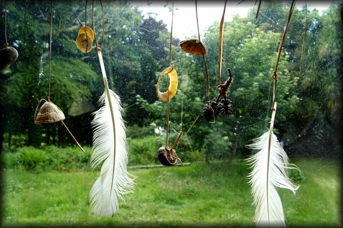 From the common room at the Old Monastery Hostel. Feathers and stuff dangling from the window and blurry garden behind.