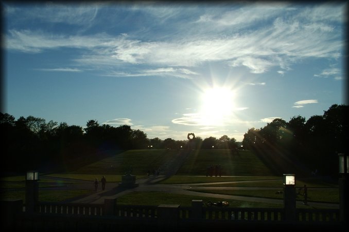 The sun is low on the Vigeland Sculpture Park. Glimpse of the Wheel of life above the threes and under the sun.