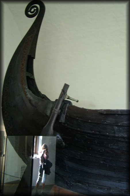 Tiny me. Reflection in the protective glasse case near the stern of the huge-looking Oseberg Ship at the Viking Ship Museum.