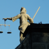 The scales of Justice. Justitia has frequently been depicted as a bare-breasted woman carrying a sword and scales, and sometimes wearing a blindfold.