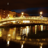 Illuminated bridge over River Liffey. The light at the top on the left is the tip of the Spike of Dublin.