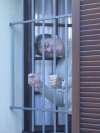 Stephane at the window smiling behind the bars