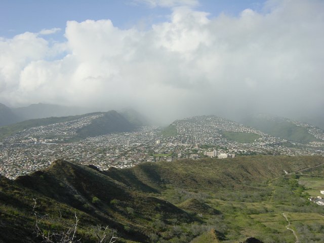 View on the houses-covered hills, and a rain cloud in a half-pipe between two hills