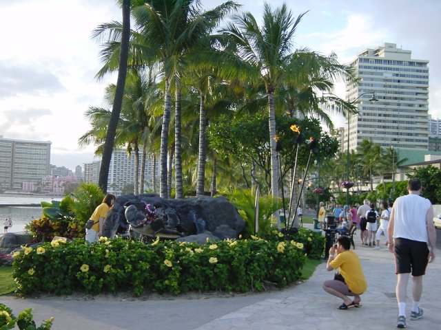 Japanese couple dressed in yellow and taking pictures of a fountain by the ocean