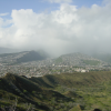 View on the houses-covered hills, and a rain cloud in a half-pipe between two hills