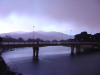 Bridge over the river and heavy clouds over the mountains