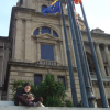 A young woman reading on stairs in front of the MNAC, flags (europe, catalunya, spain, unidentified)